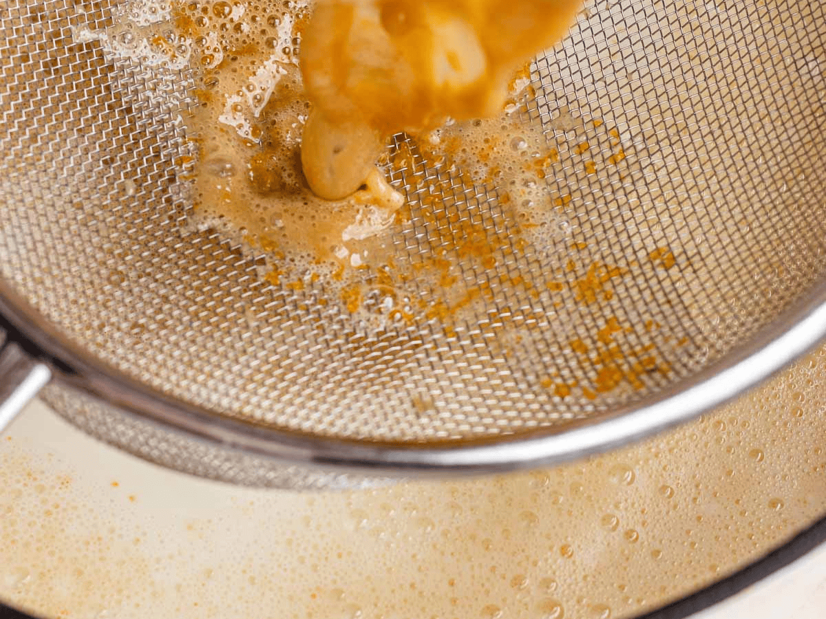 Liquid being poured through mesh strainer.