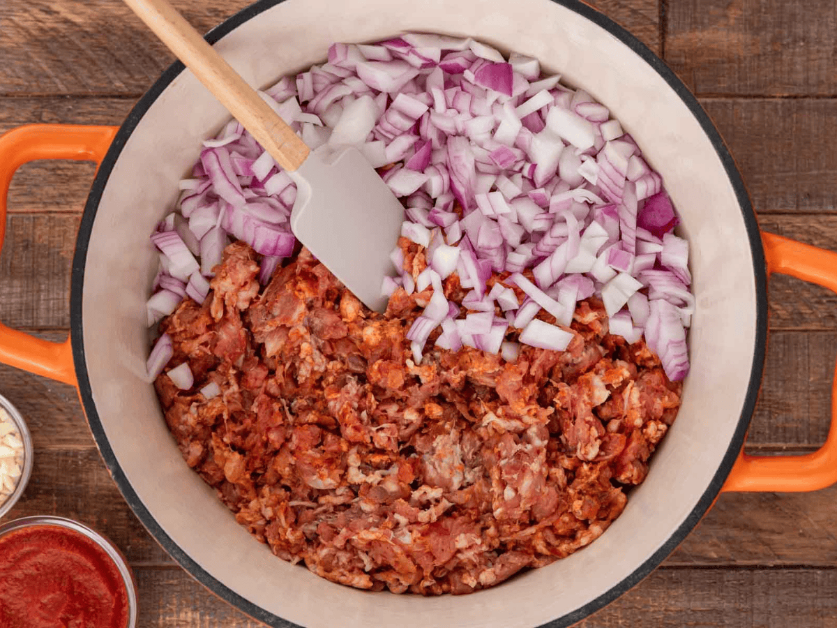 Meat and onions in a white pot.
