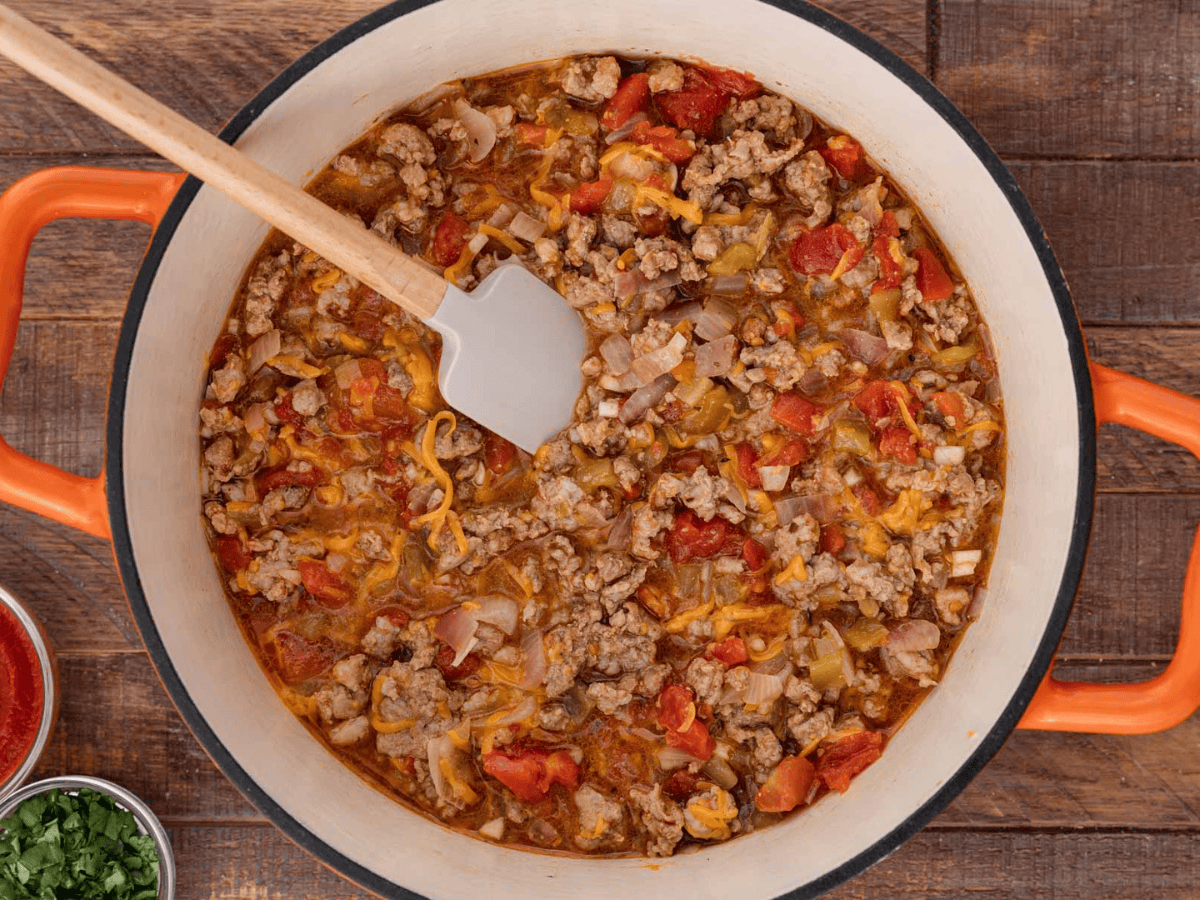 Cooked meat in a pot mixed with cheese and tomatoes.