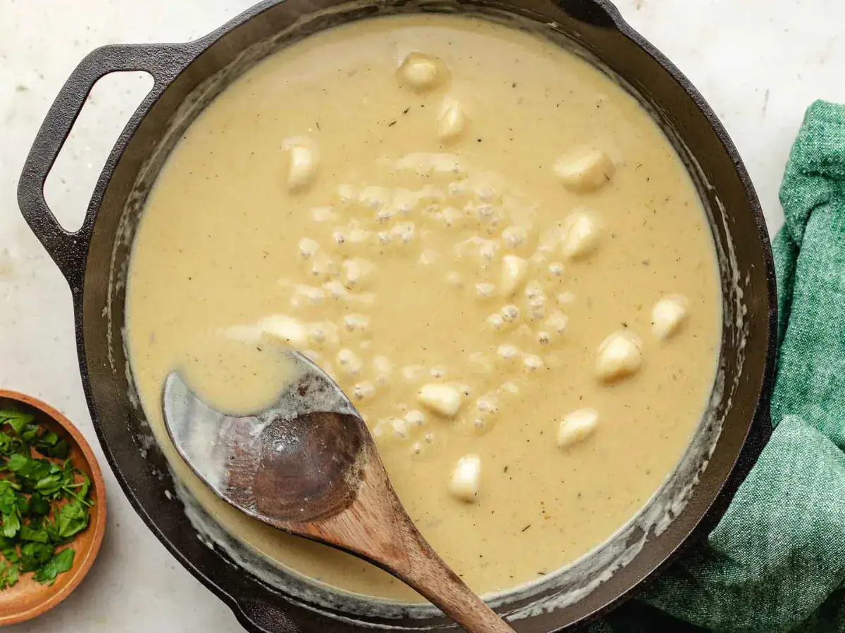 Tan colored gravy with whole garlic cloves.