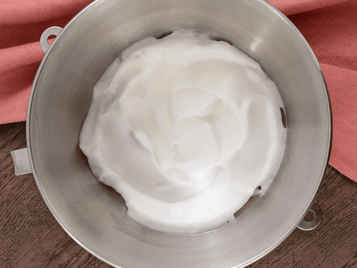 Silver mixing bowl with a white fluffy egg whites.