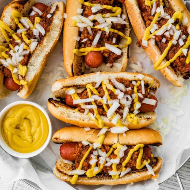 Hot dogs topped with chili, mustard, and onion.