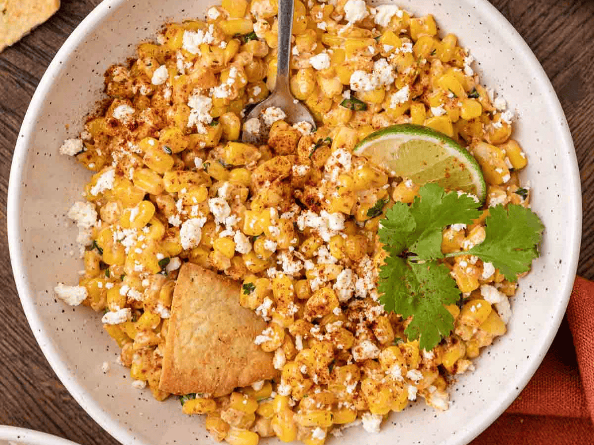 Bowl with corn kernel salad, topped with cheese and cilantro.