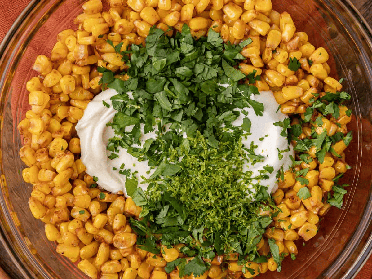 Large bowl with unmixed corn kernels, cilantro, and mayo.