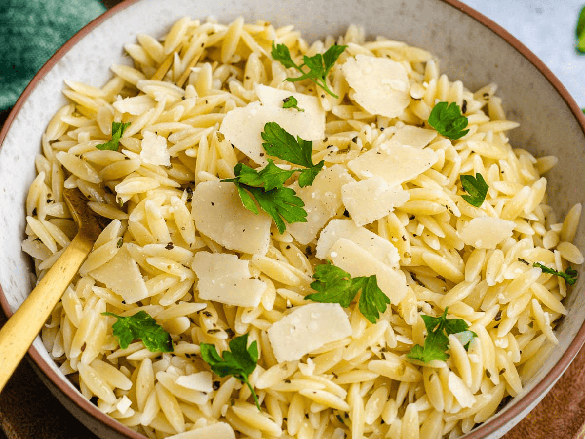 Close up view of completed pasta dish in a cream bowl.