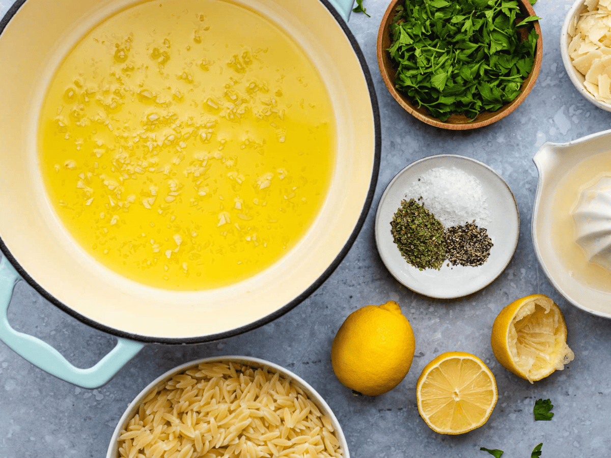 Yellow liquid in a pot surrounded by small bowls with ingredients.