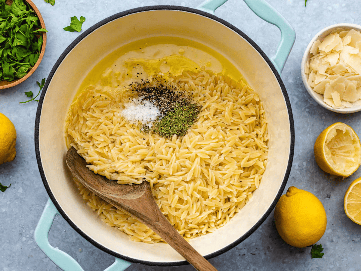 White pot with pasta and other ingredients ready to be mixed.