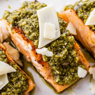 Zoomed in image of a pink fish with green sauce and white cheese.