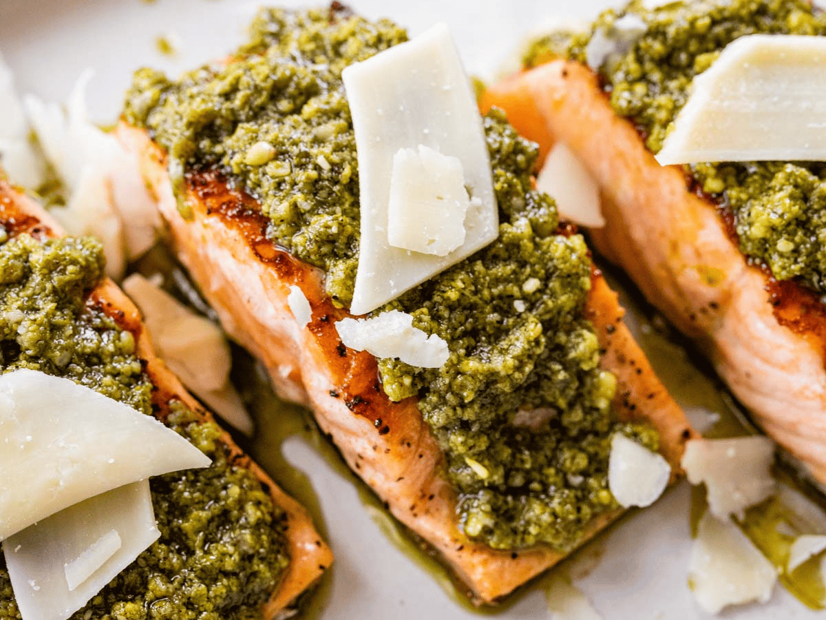Zoomed in image of a pink fish with green sauce and white cheese.