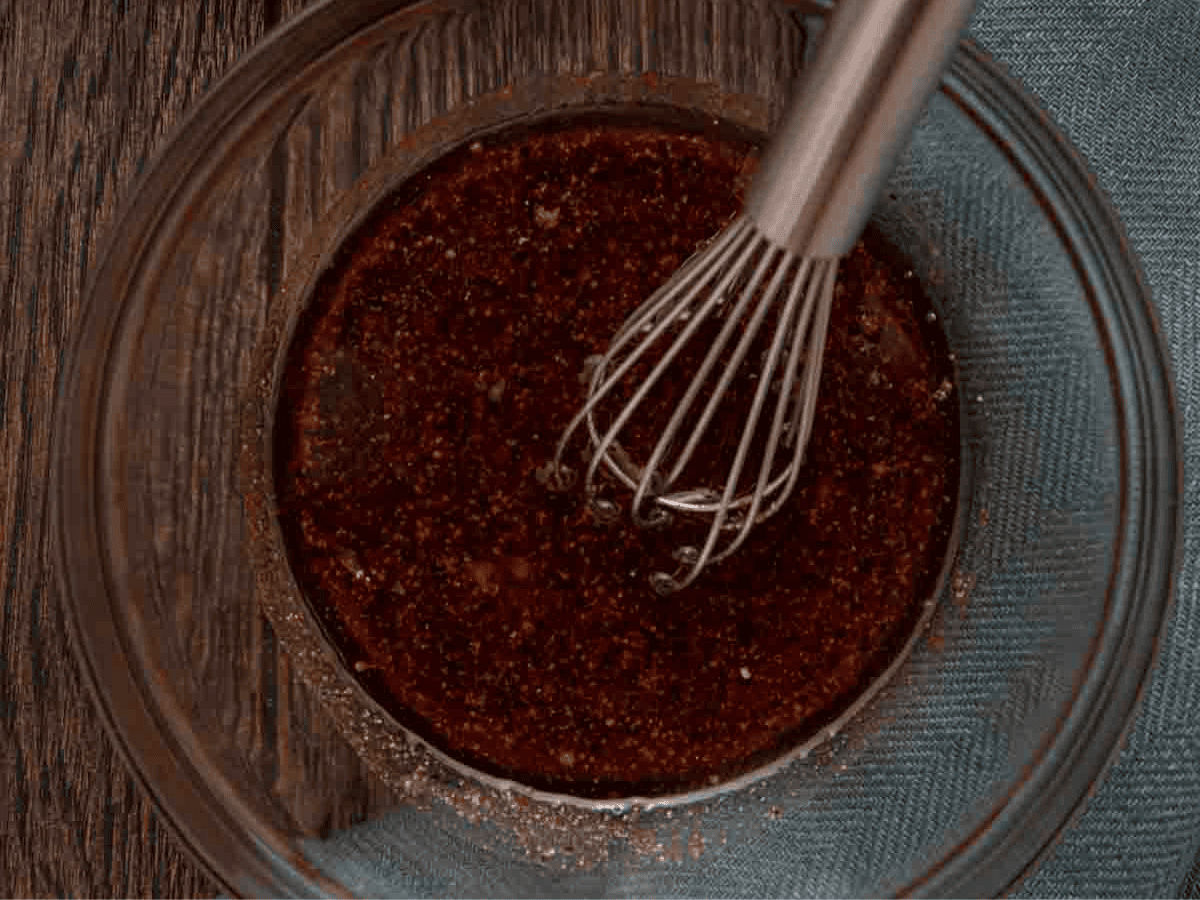 Meat marinade in bowl with whisk.
