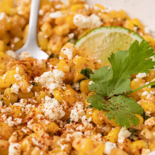 Bowl of corn kernels with cotija and lime.