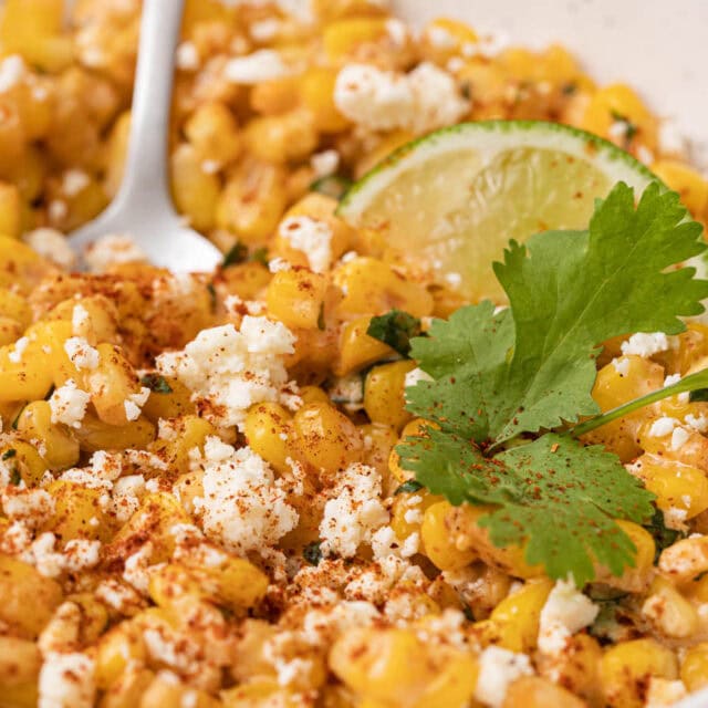 Bowl of corn kernels with cotija and lime.