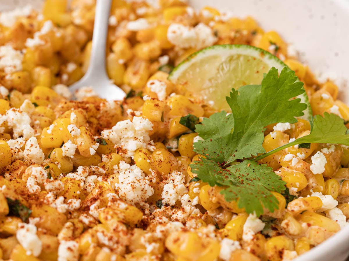 Bowl of corn kernels with cotija and lime.