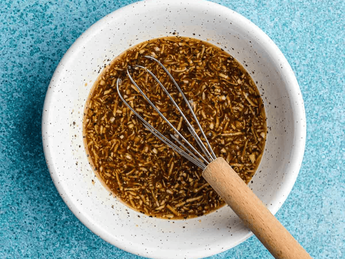 Homemade dressing in bowl with whisk.