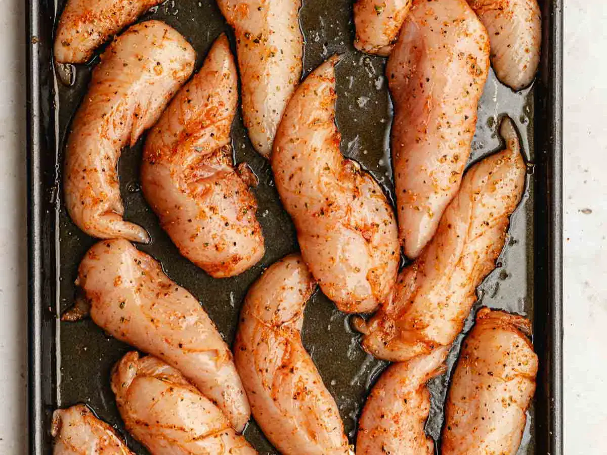 Seasoned, raw poultry on baking sheet.