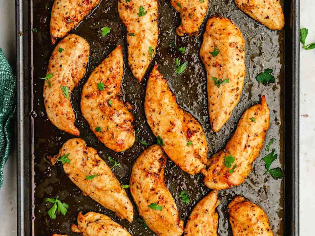 Seasoned and baked chicken on baking sheet.