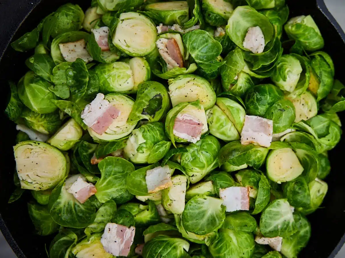 Raw veggies and bacon in cast iron pan.