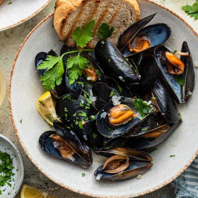 Bowl of mussels in shell with bread.
