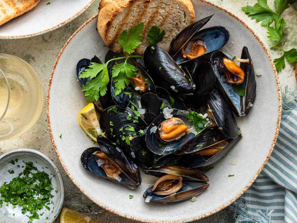 Bowl of mussels in shell with bread.