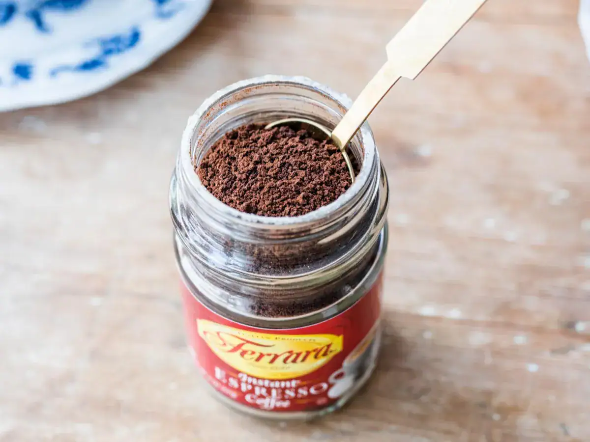 Glass of instant espresso with a gold spoon in it.