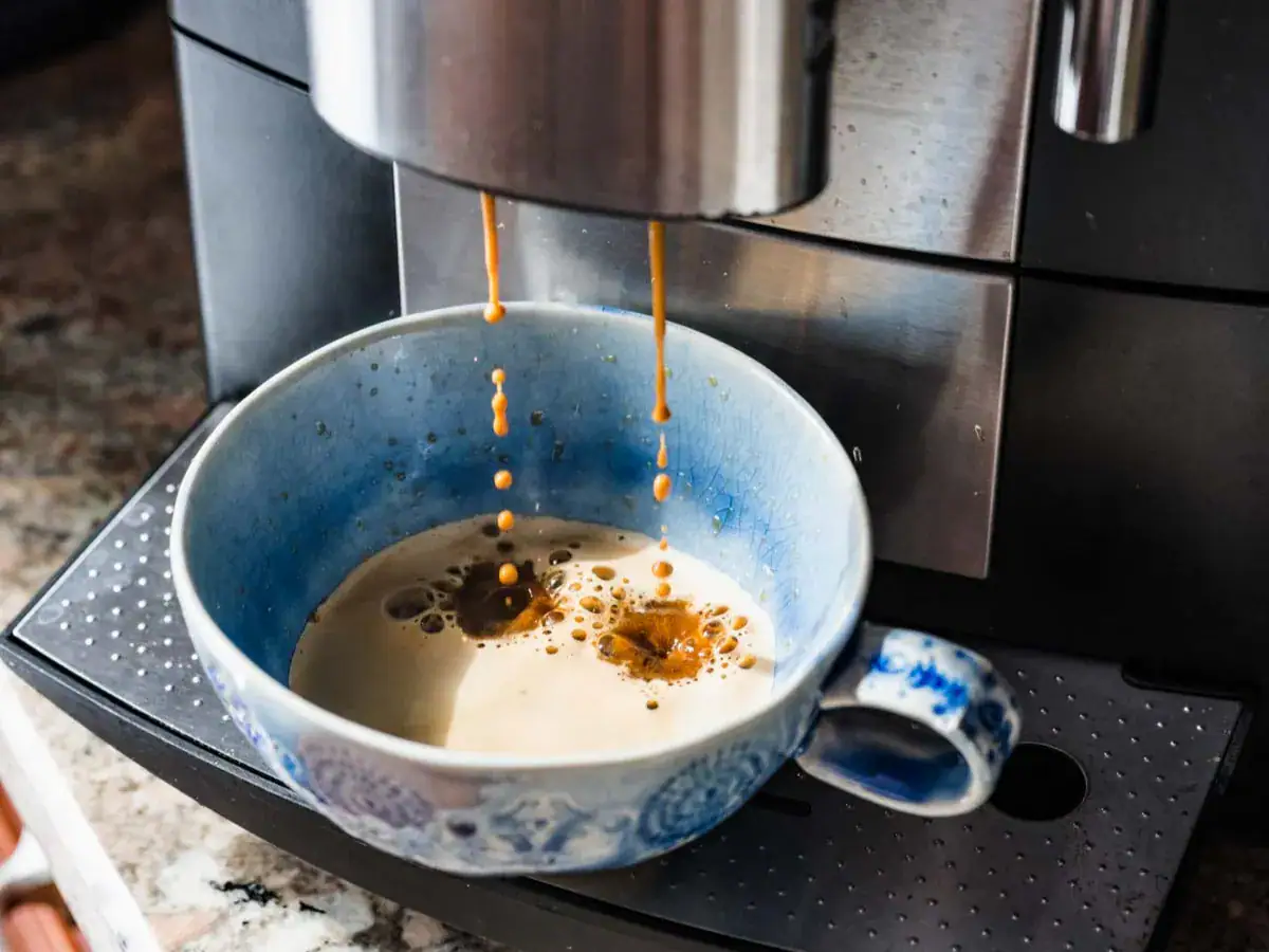 Coffee being made in a light blue mug by an espresso maker.