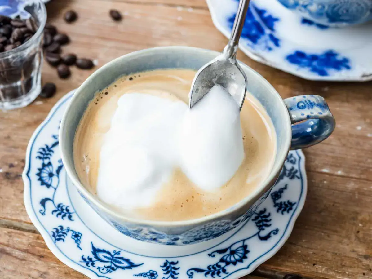Coffee mixture in a blue mug being topped with foam.