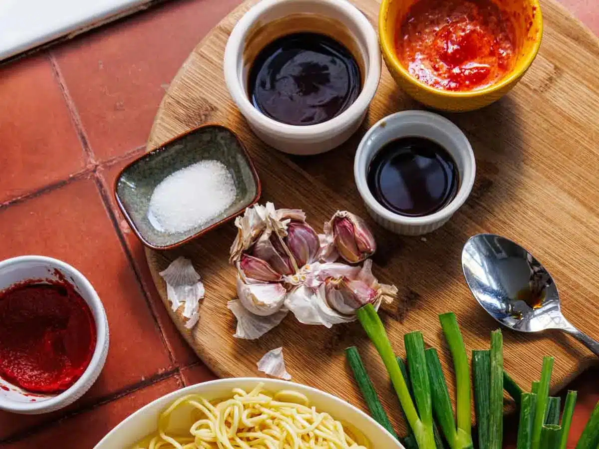 Ingredients for spicy stir fry sauce and noodles spread on cutting board