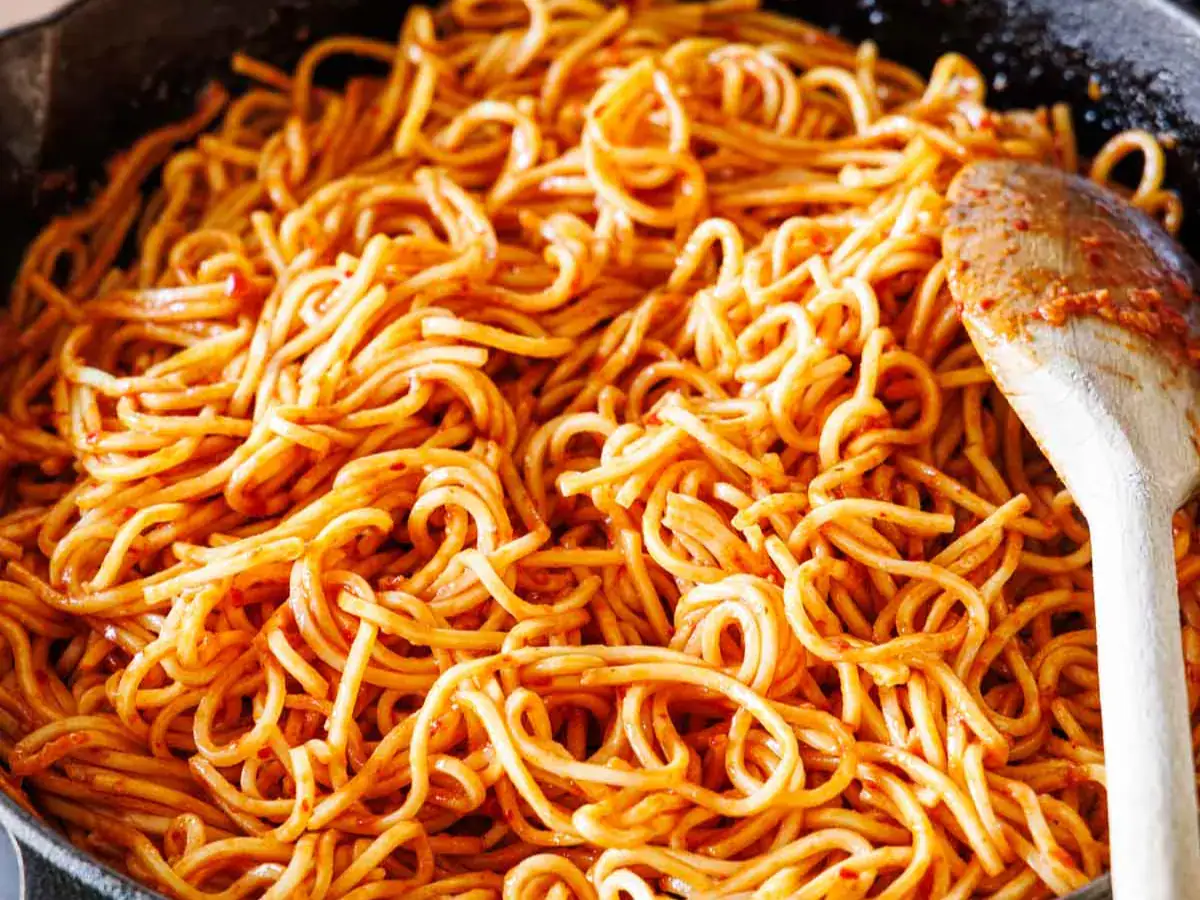 Chow mein noodles coated in sauce in pan.