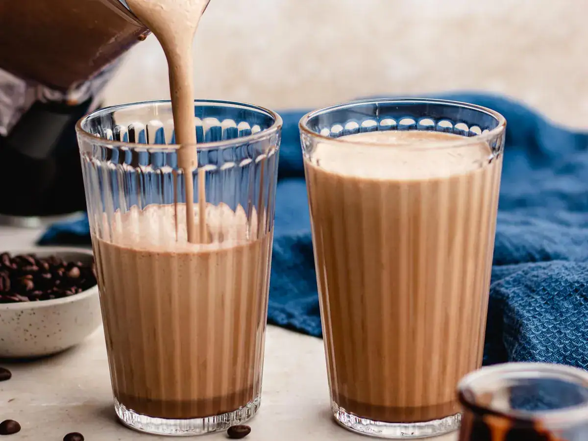 Blended frozen coffee drink being poured into glasses.