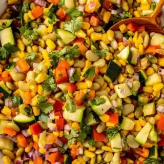 Close up of side dish with corn, peppers, zucchini, and beans.