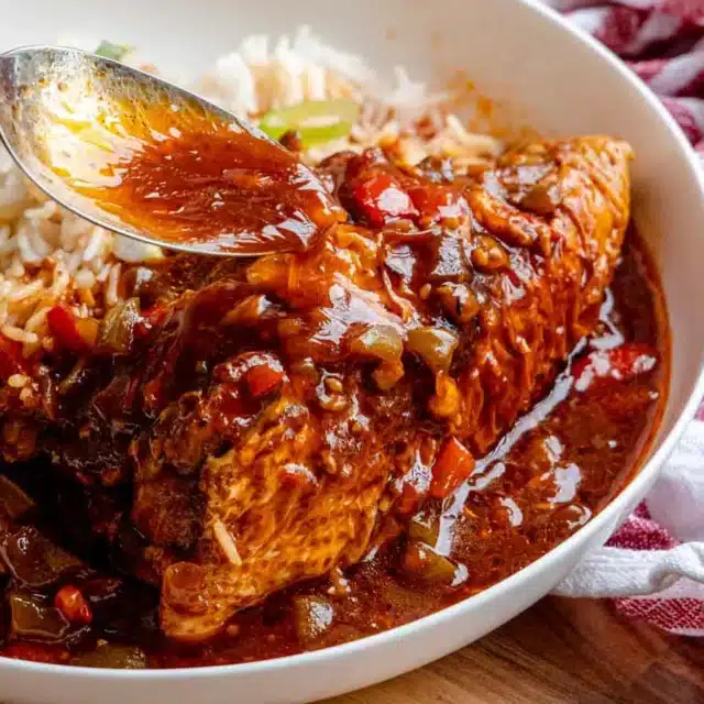 Chicken in sauce with rice on dinner plate.