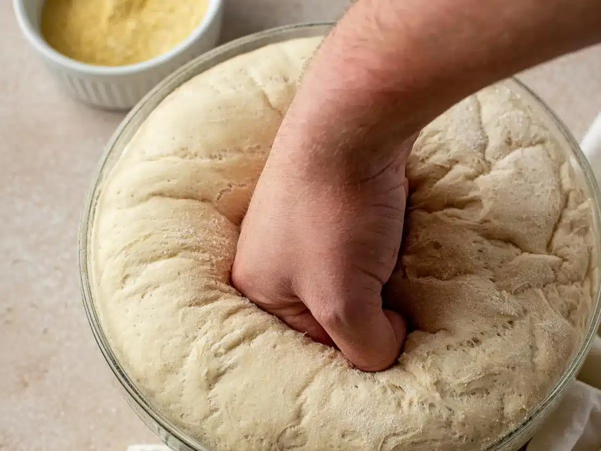 Risen dough being punched by hand.