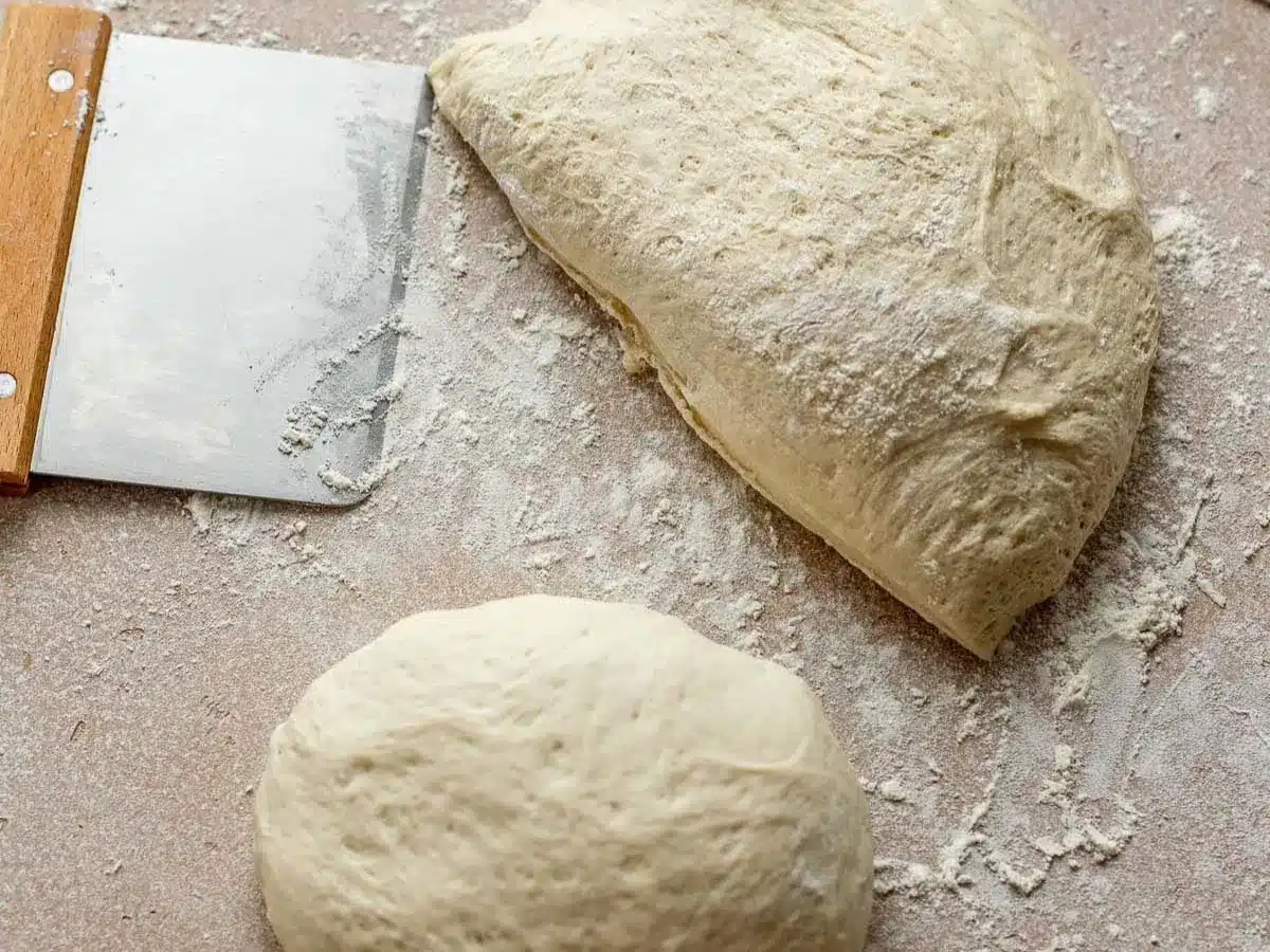 Ball of risen dough cut into pieces.