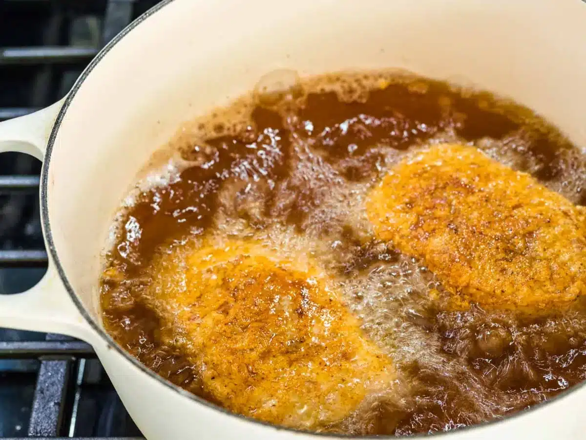 Seasoned flour coated meat chops frying in oil.