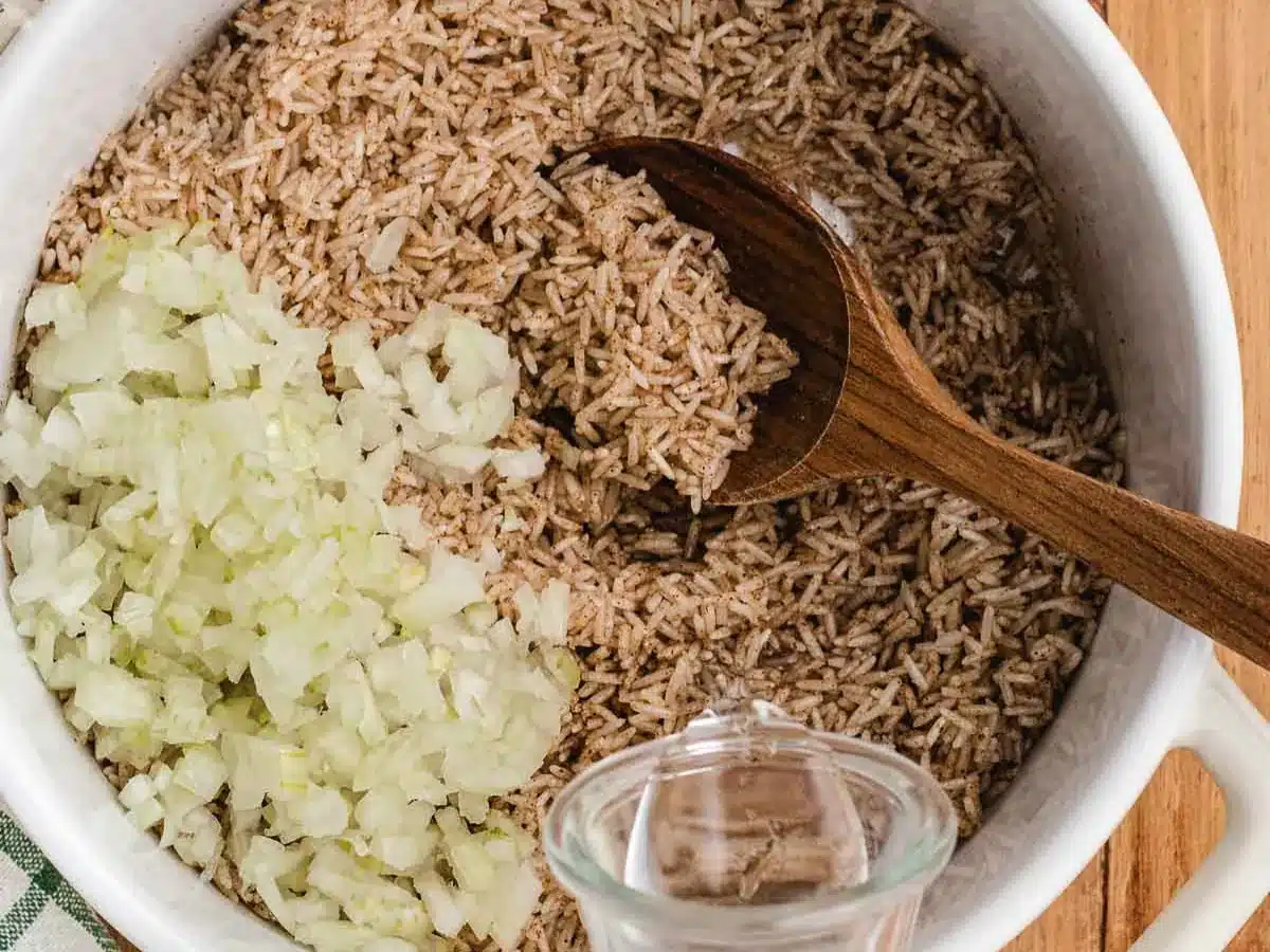 Diced onion being added to seasoned rice.