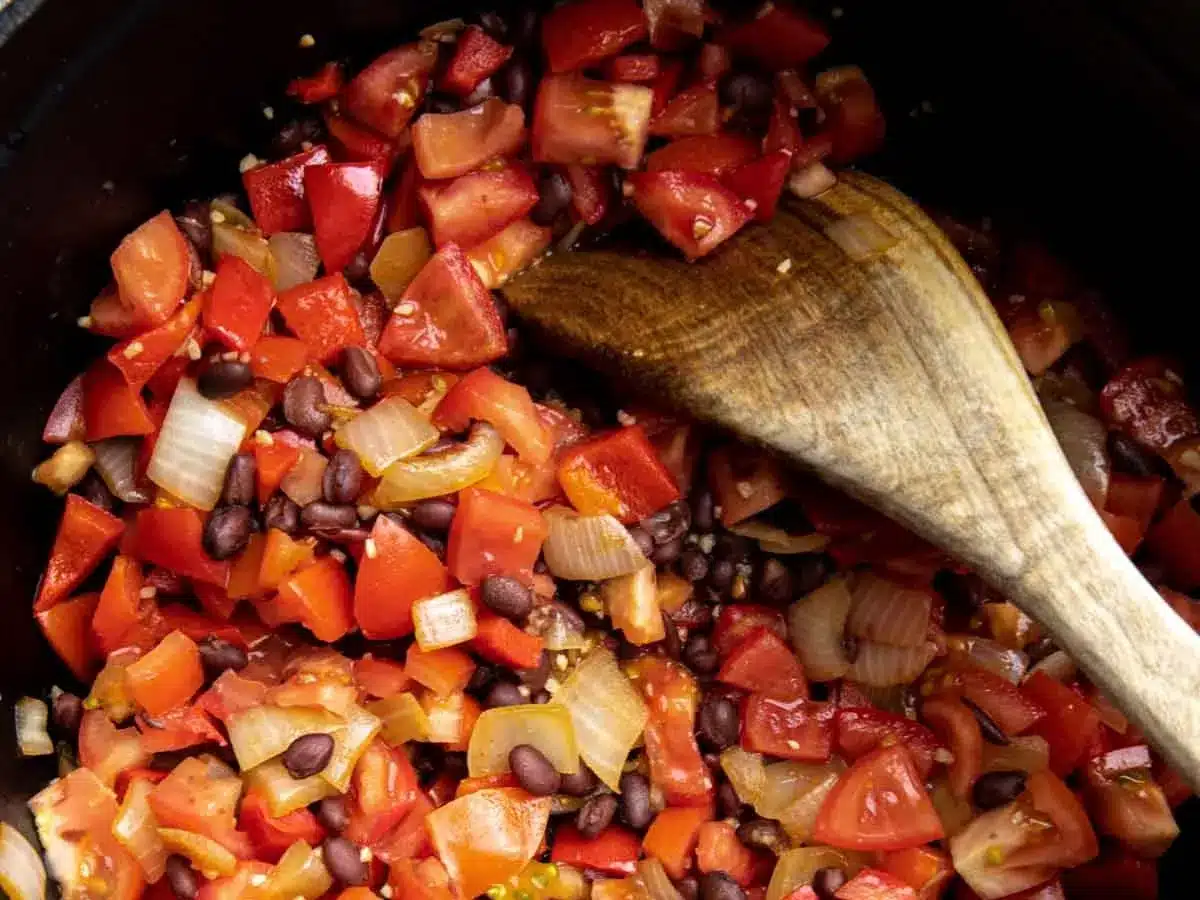Diced vegetables and beans sautéing in pot.