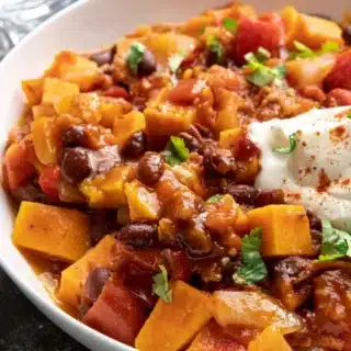Bowl of vegetarian chili, topped with sour cream.