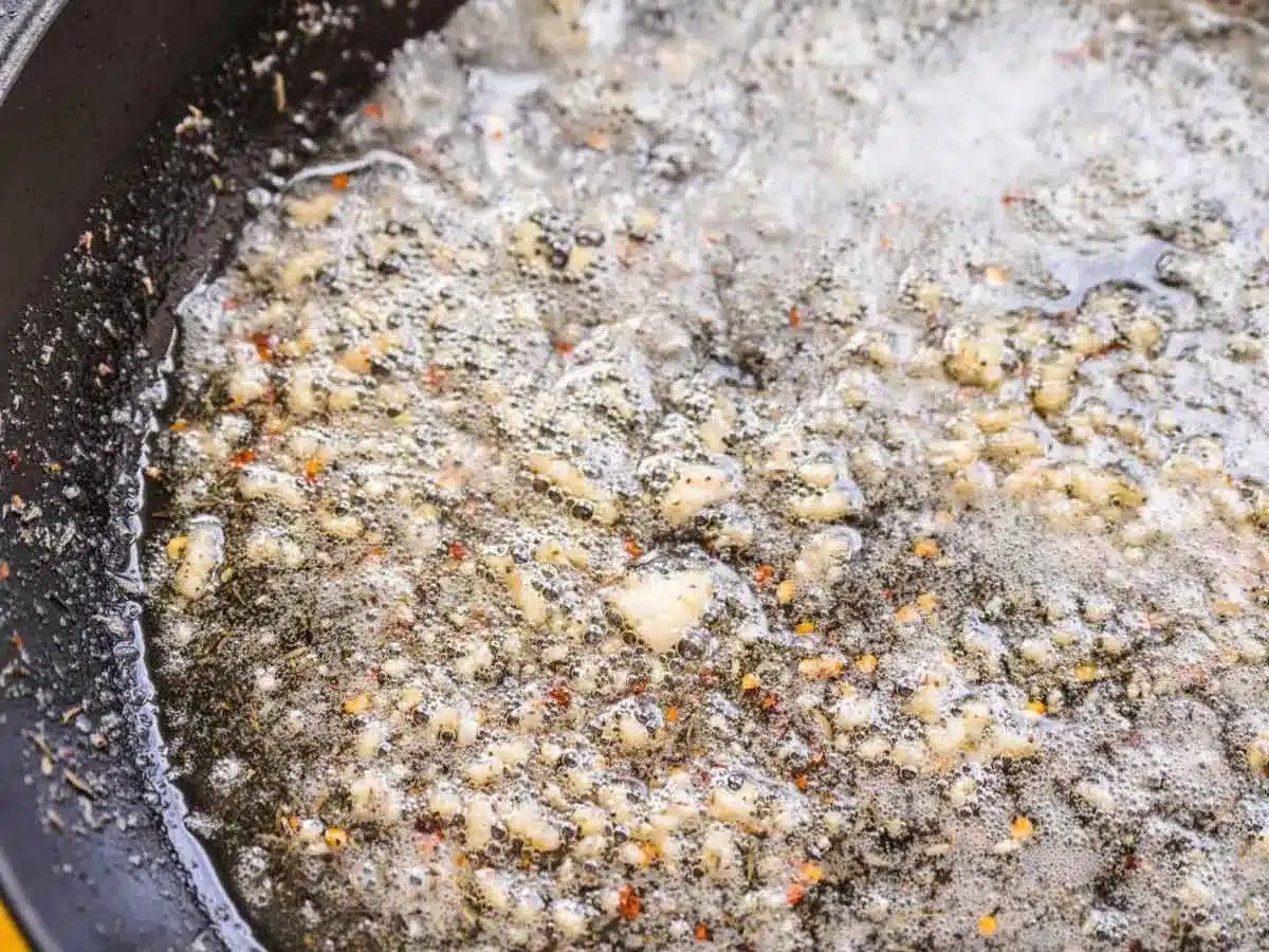 Minced garlic and olive oil sautéing in pan. 