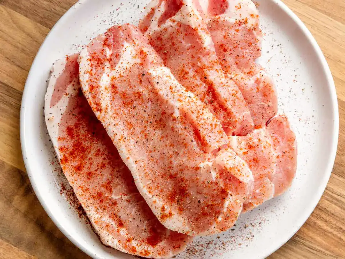 Seasoned pork on plate, ready to cook.