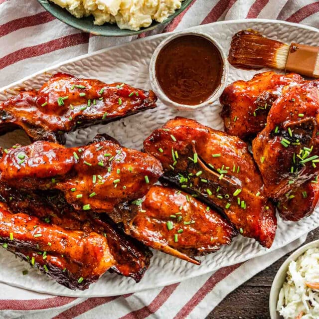 Cooked ribs with sauce on platter with cup of sauce