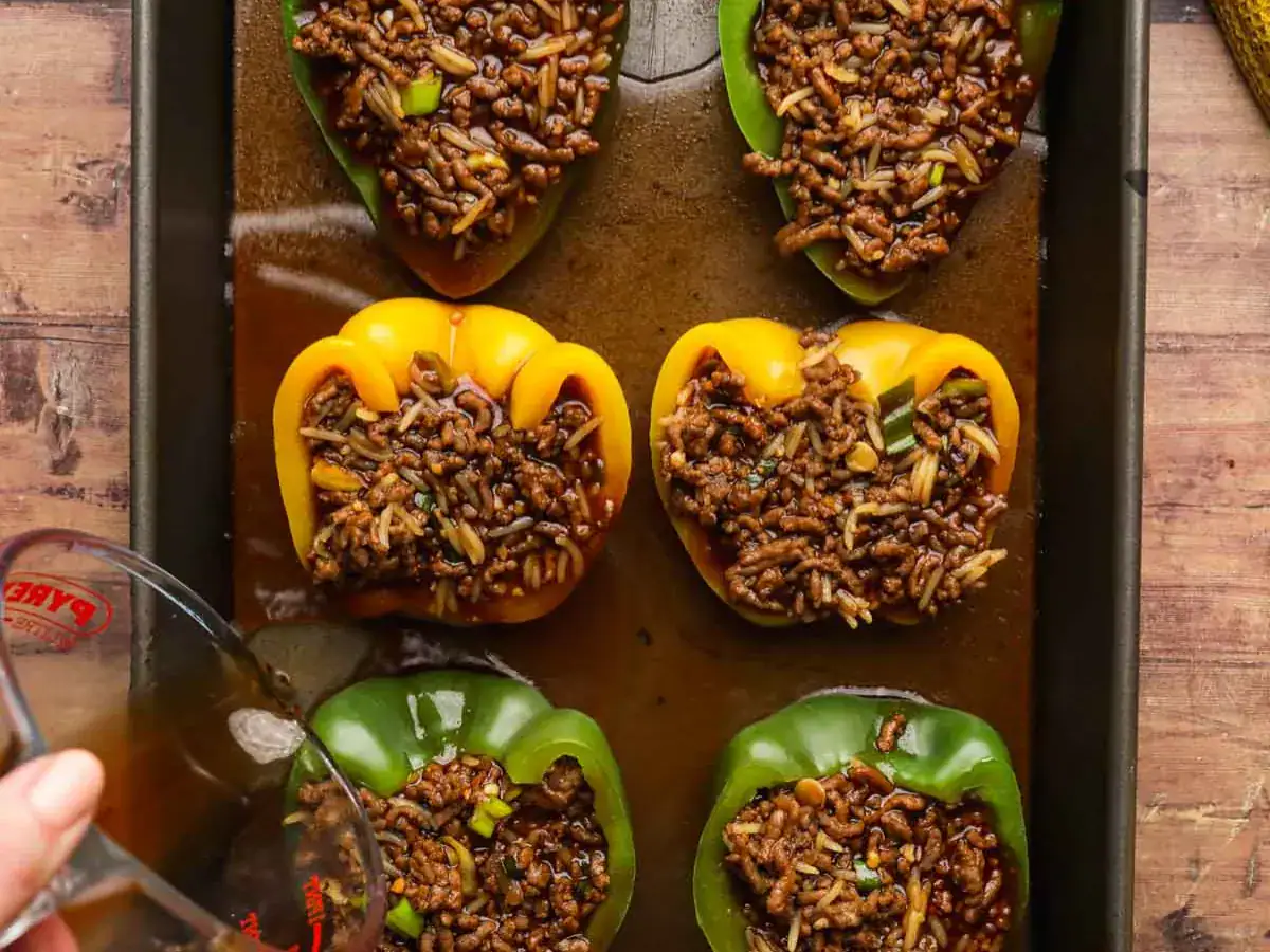 Bell peppers filled with rice and meat on baking sheet.