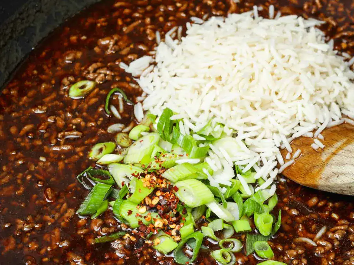 Rice and scallions added to a beef and sauce mixture.