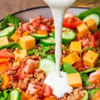 Creamy dressing being poured onto salad.
