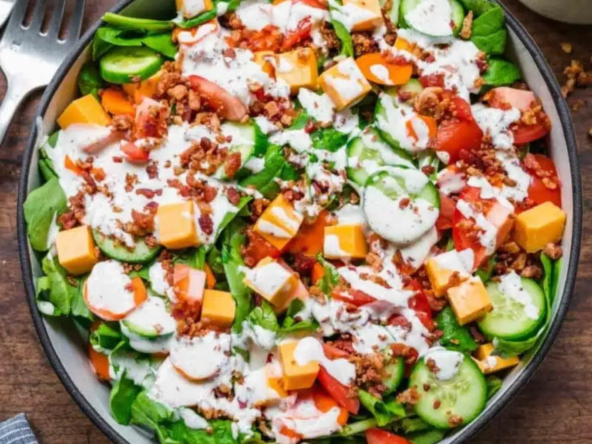 Green salad with creamy dressing, cheese cubes, and bacon.