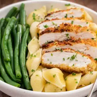 Dinner plate with pan fried chicken breast, pasta, and green beans.