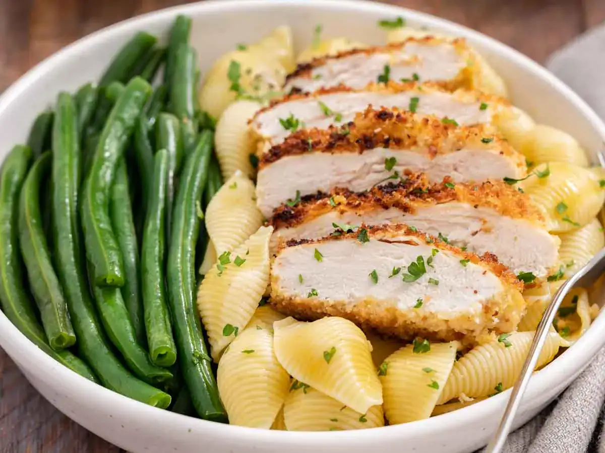 Dinner plate with pan fried chicken breast, pasta, and green beans.
