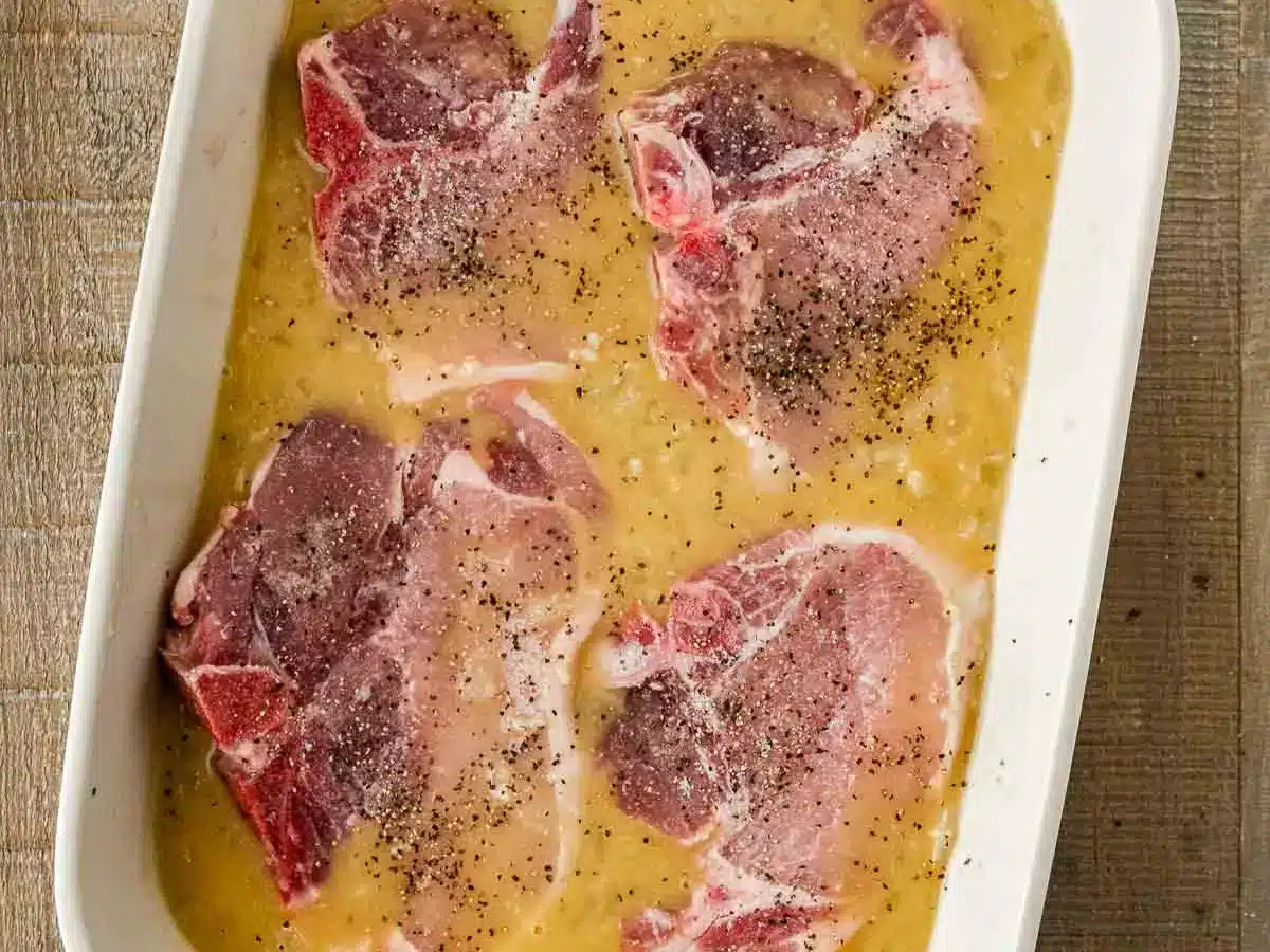 Raw chops and broth in baking dish.